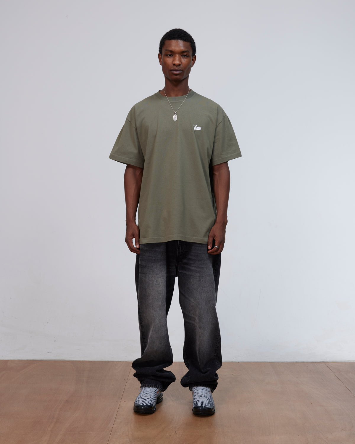 Front view of a model wearing the Patta Championship T-Shirt in dusty olive cotton jersey.
